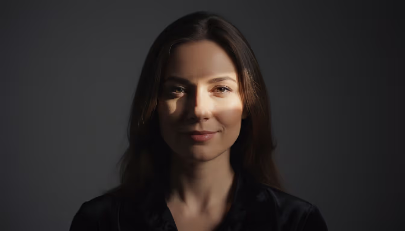 Close-up portrait of a woman demonstrating Rembrandt lighting technique with a triangle of light on the shadowed cheek against a dark background